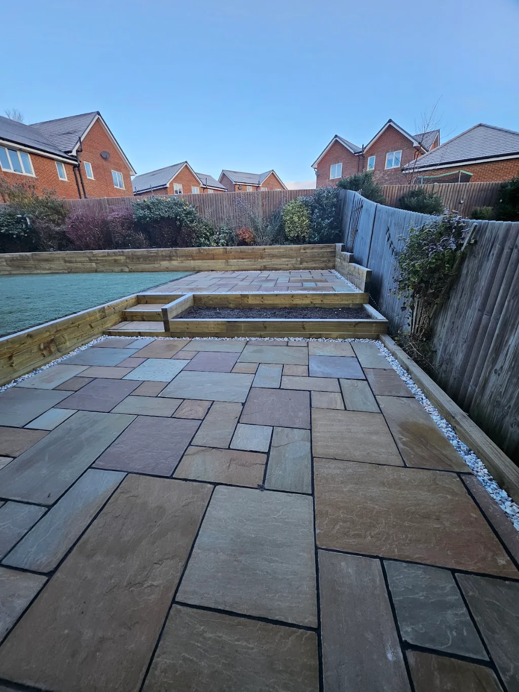 Tiered garden with sleeper retaining walls, steps and a raised sandstone patio
